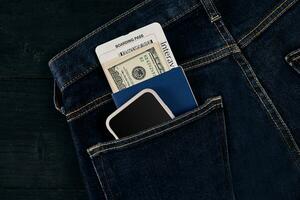 dólares, inteligente, Passaporte e avião bilhete dentro seu bolso jeans. foto