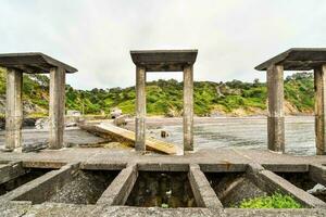 a velho concreto pilares estão em a costa do a água foto