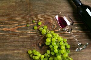 copos, garrafa do vermelho vinho e uva em uma de madeira mesa foto