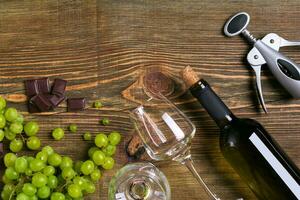 branco vinho garrafa, uva, chocolate e óculos sobre de madeira mesa. topo Visão com cópia de espaço foto