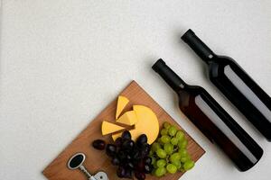 dois garrafas do branco e vermelho vinho, queijo e uvas. topo Visão foto