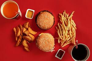 hamburguer e salgadinhos. Hamburger e francês fritas dentro vermelho papel caixa. velozes Comida em vermelho fundo. foto