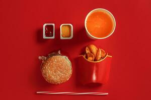 hamburguer e salgadinhos. Hamburger e francês fritas dentro vermelho papel caixa. velozes Comida em vermelho fundo. foto