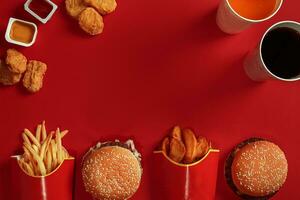 hamburguer e salgadinhos. Hamburger e francês fritas dentro vermelho papel caixa. velozes Comida em vermelho fundo. foto