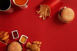 hamburguer e salgadinhos. Hamburger e francês fritas dentro vermelho papel caixa. velozes Comida em vermelho fundo. foto