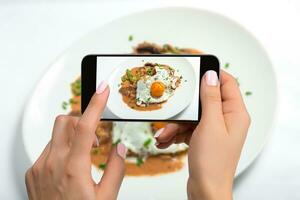 tiroteio Comida em telefone Câmera, frito ovos em uma branco prato com cogumelo em uma branco mesa, Comida fotógrafo. foto