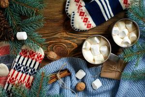 dois copos do quente cacau ou chocolate com marshmallow, luvas, Natal decoração e abeto árvore em de madeira rústico fundo a partir de acima. foto