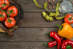 esporte e dieta. legumes e centímetro. pimentas, tomates, salada em rústico fundo foto