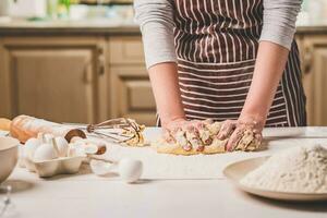 mulher mãos amassar massa em cozinha mesa foto