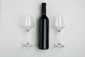 a sobrecarga angular Visão do uma ampla garrafa do vermelho vinho, bebendo óculos em branco fundo foto