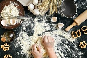 mulher mãos amassar massa em mesa com farinha, ovos e ingredientes. topo visualizar. foto