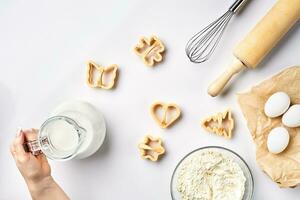 objetos e ingredientes para cozimento, plástico Bolores para biscoitos em uma branco fundo. farinha, ovos, rolando alfinete, bata, leite, manteiga, creme. topo visualizar, espaço para texto foto