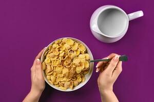 comida, saudável comendo, pessoas e dieta conceito - fechar acima do mulher comendo muesli com leite para café da manhã sobre roxa fundo foto