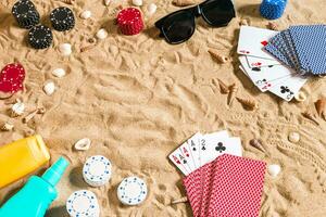 poker de praia. salgadinhos e cartões em a areia. por aí a conchas, oculos de sol e bronzeado creme. topo Visão foto