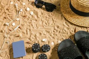 poker de praia. salgadinhos e cartões em a areia. por aí a conchas, oculos de sol e giro fracassos. topo Visão foto