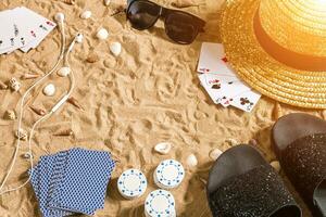 poker de praia. salgadinhos e cartões em a areia. por aí a conchas, oculos de sol e giro fracassos. topo Visão foto