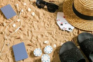 poker de praia. salgadinhos e cartões em a areia. por aí a conchas, oculos de sol e giro fracassos. topo Visão foto