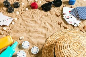 poker de praia. salgadinhos e cartões em a areia. por aí a conchas, oculos de sol e chapéu. topo Visão foto