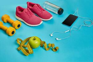 saudável conceito, dieta plano com esporte sapatos e garrafa do água e halteres em azul fundo, saudável Comida e exercício conceito foto