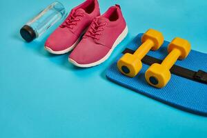 saudável conceito, dieta plano com esporte sapatos e garrafa do água e halteres em azul fundo, saudável Comida e exercício conceito foto