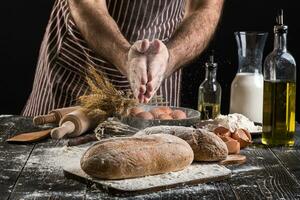 chefe de cozinha granulados fresco pão com farinha. homem preparando massa às mesa dentro cozinha. foto