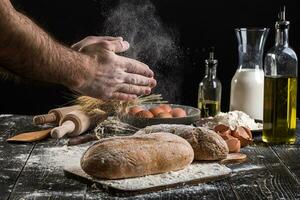 chefe de cozinha granulados fresco pão com farinha. homem preparando massa às mesa dentro cozinha. foto