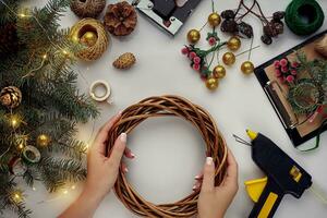 fêmea mãos decorar a Natal guirlanda com abeto galhos com uma vermelho baga e floresta cones. branco fundo. Novo anos conceito. foto