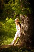 garota fica perto de uma árvore na luz do sol foto
