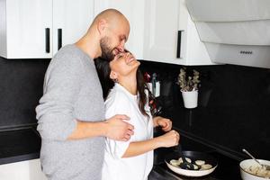 jovem marido e mulher estão cozinhando na cozinha foto