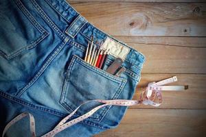 jeans com medida e giz de cera, pincéis no bolso de trás em madeira foto