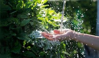 água derramando na mão da mulher no fundo da natureza, questões ambientais