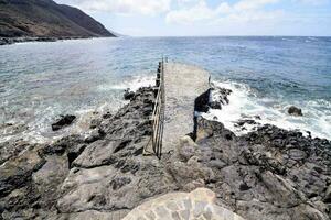 uma rochoso de praia com uma passarela conduzindo para a oceano foto