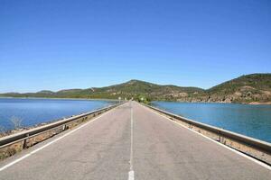 uma grandes esvaziar estrada com uma lago dentro a fundo foto