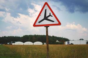 sinal de trânsito com triângulo e avião pousando no campo no céu foto