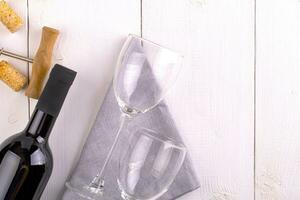 esvaziar copos, garrafa do vermelho vinho e saca rolhas em branco de madeira superfície foto
