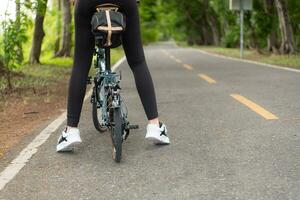 jovem mulher ciclista equitação bicicleta em estrada dentro parque. saudável estilo de vida conceito foto