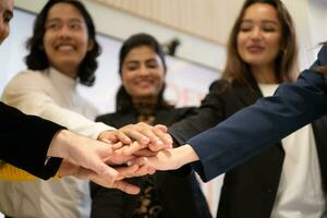 o negócio pessoas colocando seus mãos juntos Como uma símbolo do unidade e trabalho em equipe foto