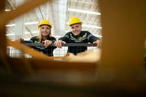 dois fábrica trabalhadores trabalhos dentro uma armazém, empurrando uma papel carrinho para estar reciclado foto