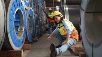 uma masculino fábrica trabalhador assistências uma fêmea industrial trabalhador quem tem a ferido perna. Como uma resultado do trabalhando com robusto e enorme objetos foto