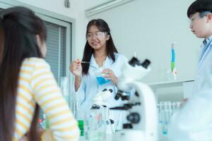 dentro a Ciência sala de aula, a ásia criança cientista experimentando com científico fórmulas com produtos químicos foto