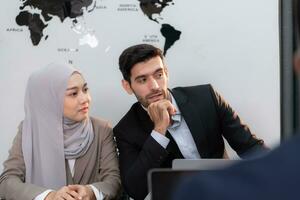 dentro uma moderno escritório, uma hijab empresária e uma homem de negocios falando e usar uma inteligente telefone enquanto dentro uma reunião. foto