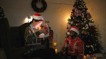 jovem mulher abertura uma presente caixa em Natal manhã às casa dentro vivo quarto foto