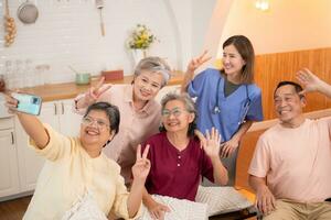 grupo do ásia Senior e cuidador tendo Diversão com selfie dentro a enfermagem lar. foto