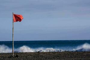 uma vermelho bandeira em a de praia perto a oceano foto