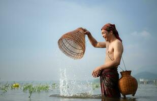 pescador usando tradicional pescaria engrenagem para pegar peixe para culinária, rural Tailândia vivo vida conceito foto
