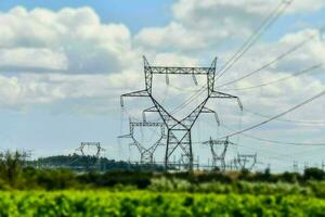 uma ampla grupo do eletricidade postes dentro a meio do uma campo foto