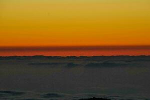 a Sol configuração sobre a nuvens foto