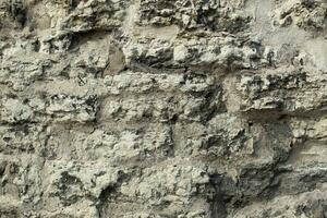 fundo desigual concreto parede dentro buracos cinzento e saliente pedras. para decoração. Alto qualidade foto