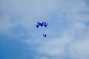 uma pessoa é parasailing dentro a azul céu foto