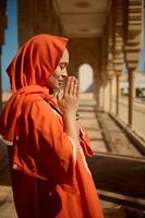 lado retrato lindo meio Oriental muçulmano mulher dentro hijab e autêntico vestir, Rezar entre a mesquita colunas foto